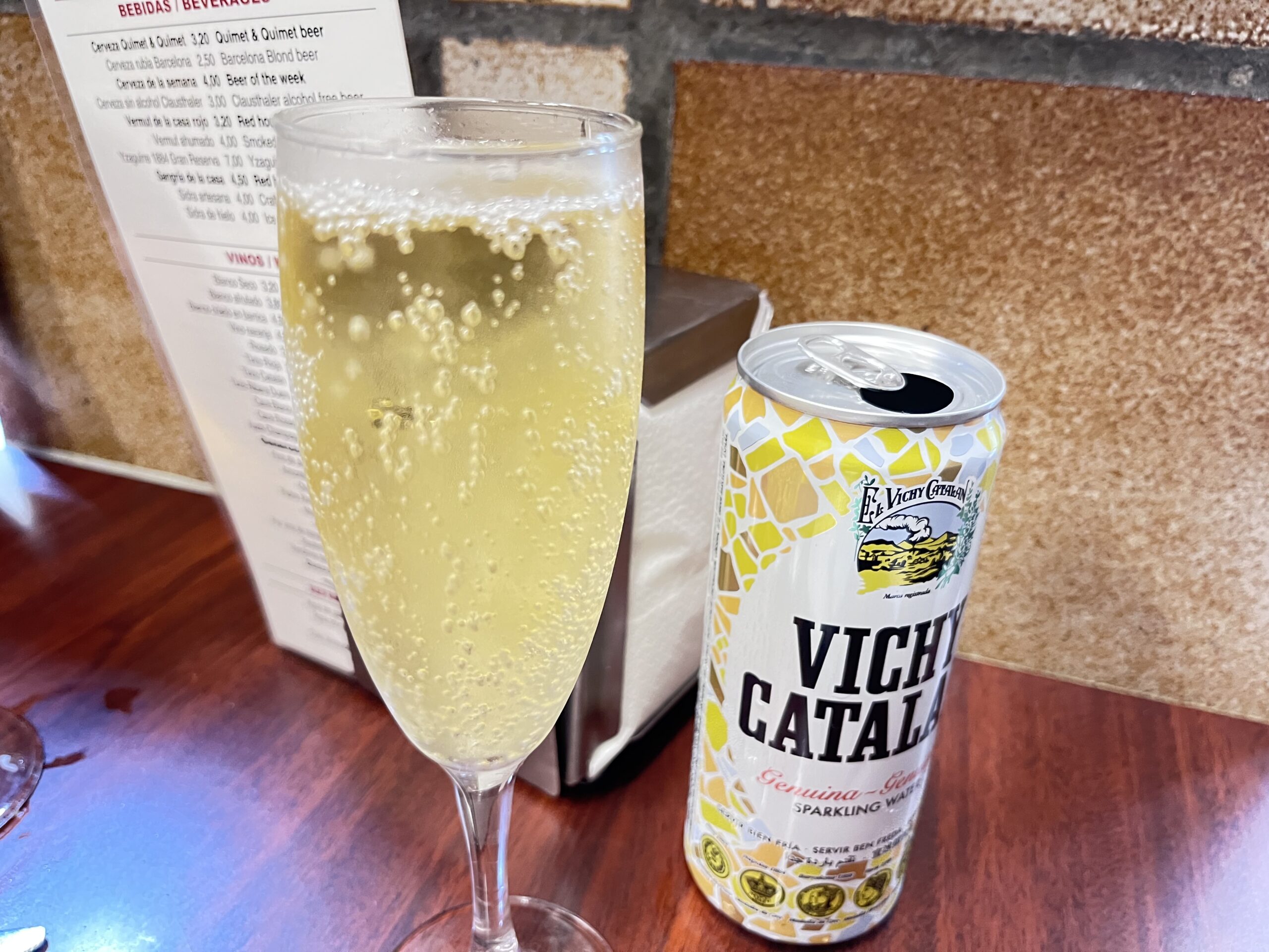 グラスにたっぷり注がれたスパークリングワインと缶入りのVICHY CATALAN炭酸水
